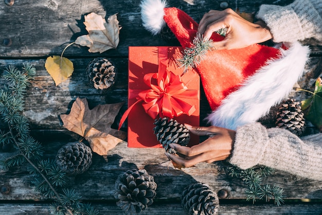 屋外の木製テーブルでクリスマスの装飾をしている女性の腕