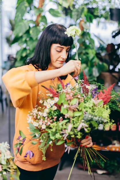 Woman arranges bouquet from flowers in florist shop small business and creative work