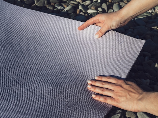 Woman arranging yoga mat on rocks