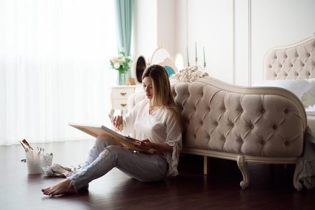 Woman artist drawing her picture on canvas with oil colors at home