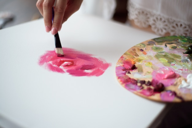 女性アーティストが自宅でキャンバスに油彩で絵を描く