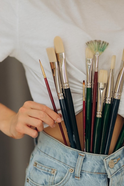 Woman artist hand choosing and picking oil paintbrushes