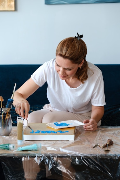 タブレットによるオンラインレッスンでアクリル塗料とスパチュラで自宅で絵を描く女性アーティスト
