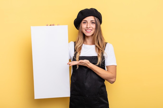 Woman artist smiling cheerfully, feeling happy and showing a concept empty canvas concept