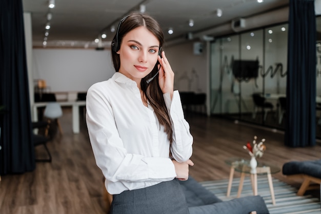 La donna come operatore di call center lavora in ufficio e parla al telefono tramite l'auricolare