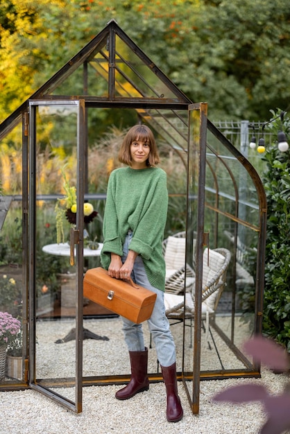 Woman as gardener near greenhouse at backyard