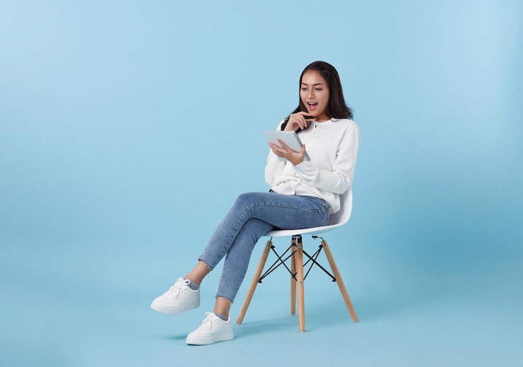 Photo アジアの女性学生が椅子に座ってノートを持ちながら幸せで考えることに興味がある