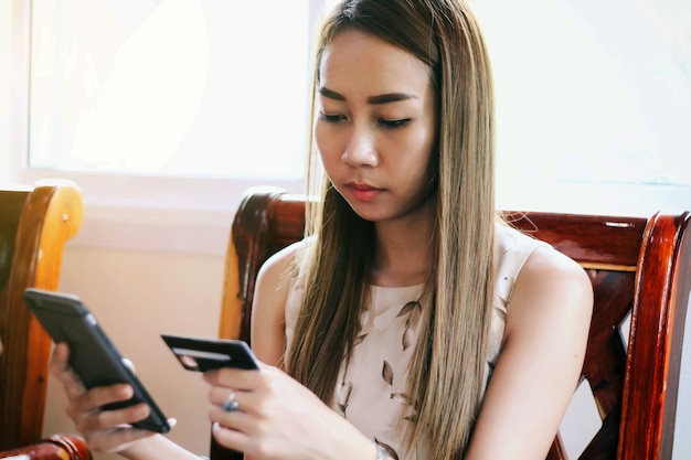 женщина-азиатка с помощью смартфона и покупки кредитных карт в Интернете