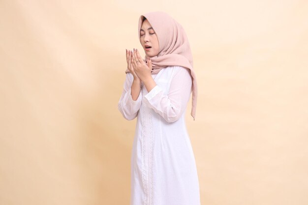 woman asian wearing a white dress hijab stands candidly covering her eyes mouth open sneezing for he