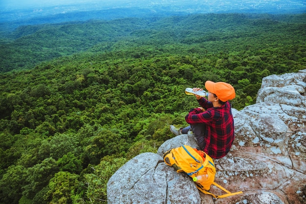 女性のアジア人の旅行は休日にリラックスします。崖の山の景色をご覧ください。