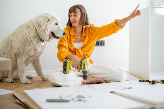 Woman Assembles Furniture At Home With Dog