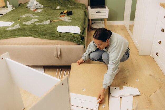 Photo woman assembling furniture at home with cordless screwdriver