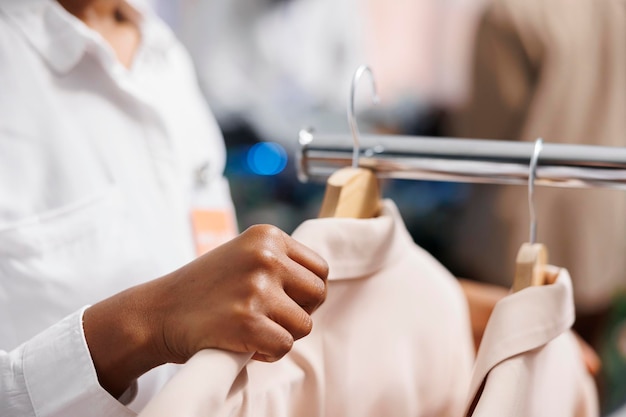 Woman assistant adjusting jackets on hangers in shopping mall