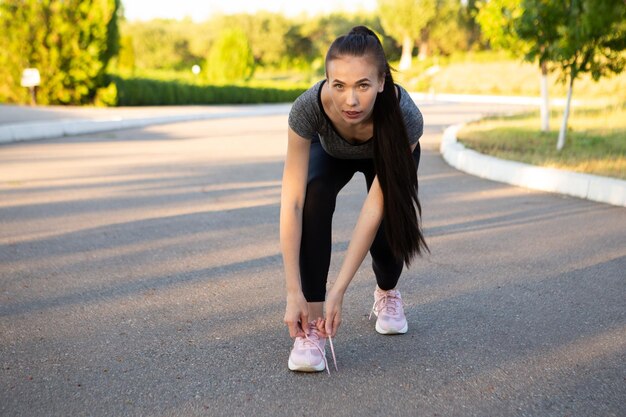 Woman athlete runner tie shoelaces and looking in camera Sporty woman preparing to run her marathon