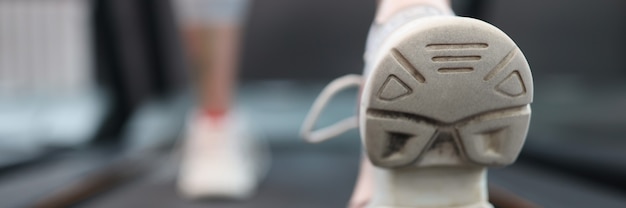 Atleta della donna che cammina sul tapis roulant nel concetto di allenamento cardio del primo piano della palestra