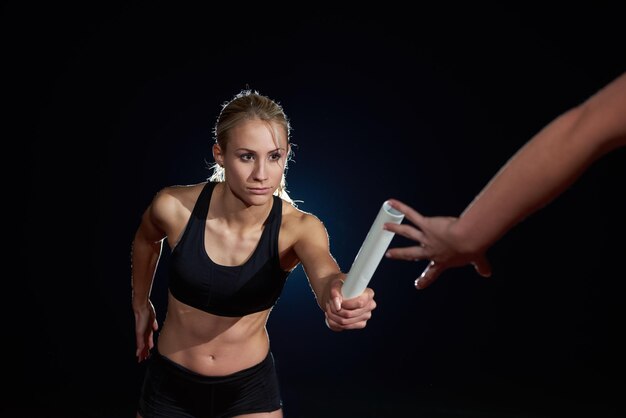 woman athletic runners passing baton in relay race