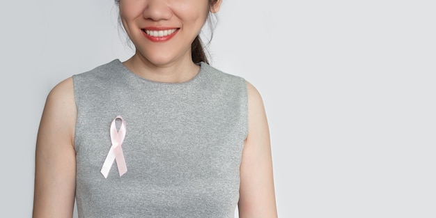 Woman attach pink ribbon bow on chest to encourage breast cancer patient A Breast cancer campaign in October month