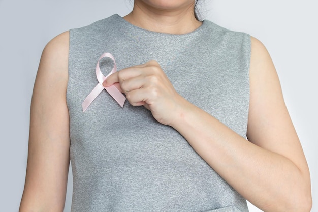 La donna attacca un fiocco rosa sul petto per incoraggiare il paziente con cancro al seno campagna contro il cancro al seno nel mese di ottobre