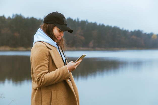 woman in autumn outfit standing at edge looking at mist lake