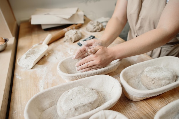 A woman baker kneads the dough and puts it in a wooden form Bakery concept