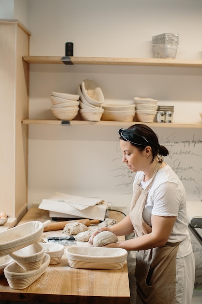 A woman baker kneads the dough and puts it in a wooden form Bakery concept