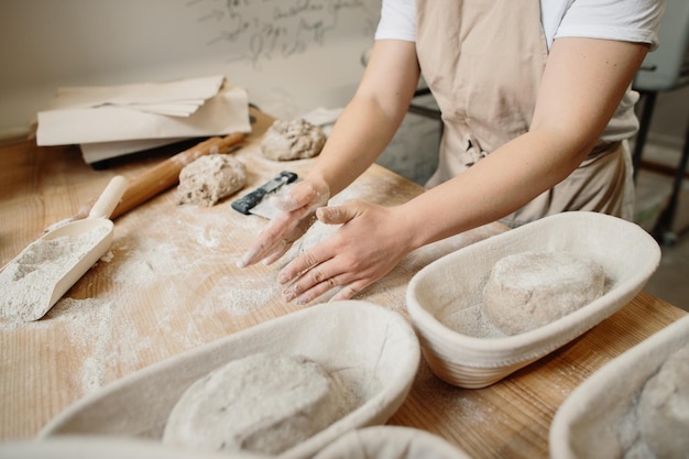 A woman baker kneads the dough and puts it in a wooden form Bakery concept