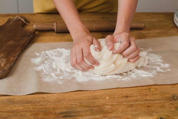 A woman baker or pastry chef kneads the dough. Close-up.