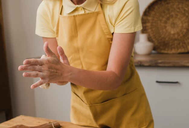 女性のパン屋またはパティシエが生地をこねます。閉じる。