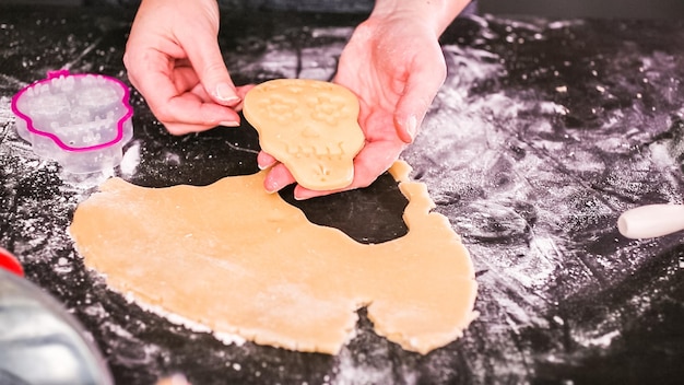 ディアデロスムエルトスの休日のために砂糖の頭蓋骨のクッキーを焼く女性。