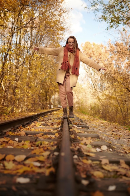 가을 배경 위에 철도에서 균형을 잡는 여자