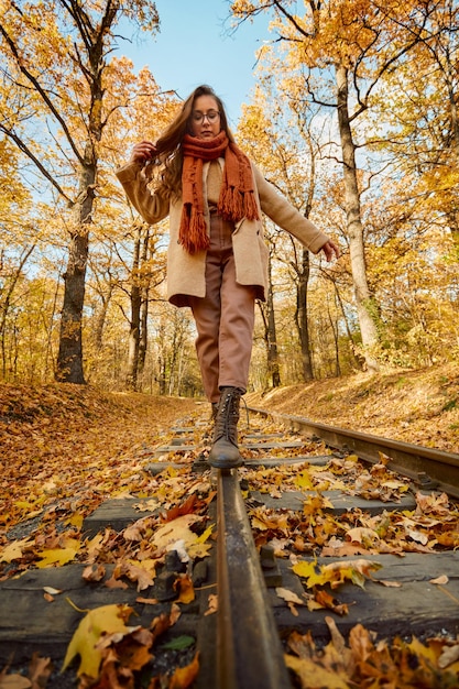 Woman balancing on railway over autumn background