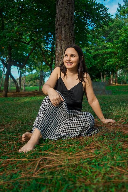 Woman barefoot sitting down on the grass in the park