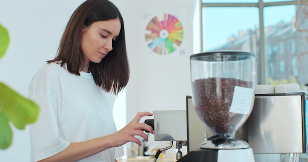 女性バリスタがコーヒー ショップ バーでカプチーノを作っています。