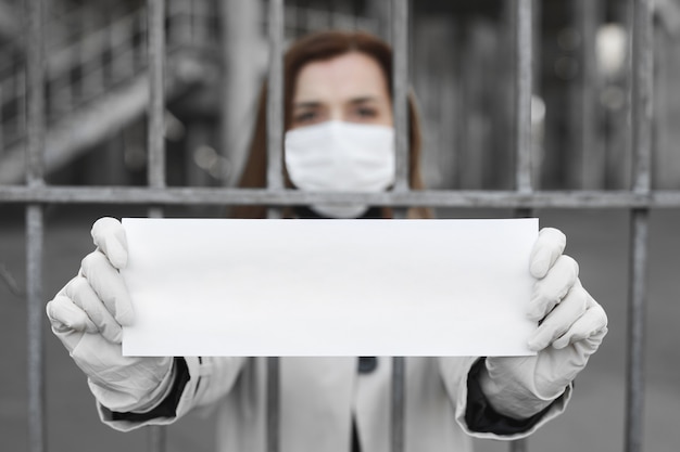 Foto la donna dietro le sbarre in isolamento tiene un cartello vuoto senza un'iscrizione