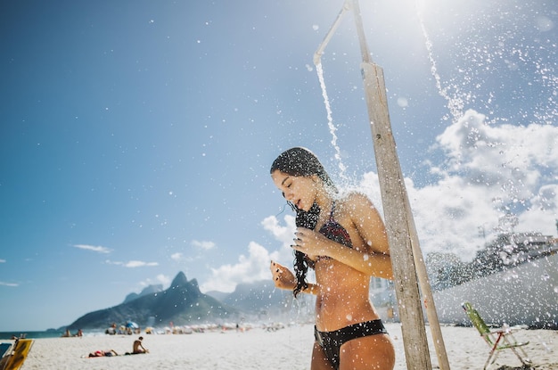空の向こうのビーチでシャワーを浴びている女性