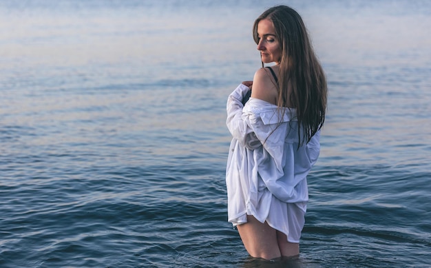 A woman in a bathing suit and a white shirt in the sea