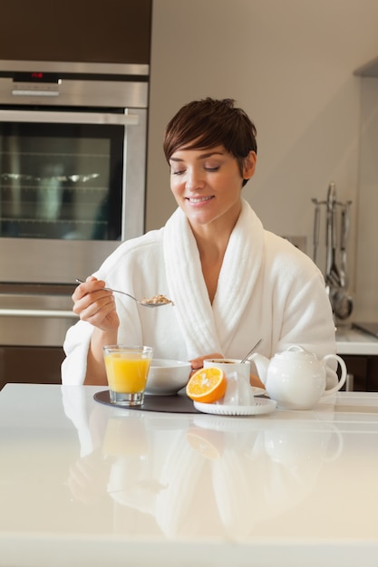 Woman in bathrobe having breakfast