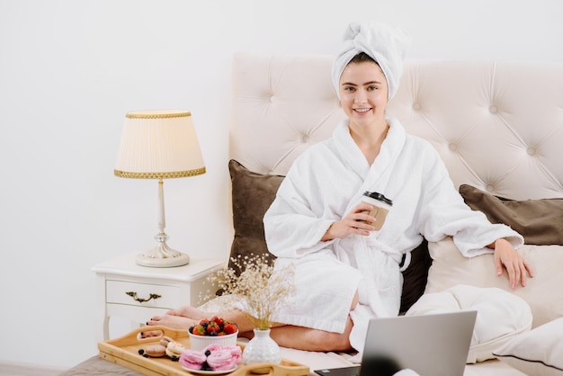 A woman in a bathrobe relaxing on the bed at home