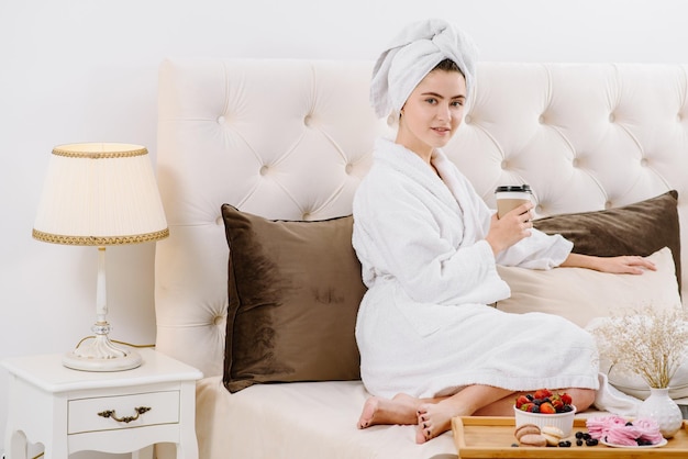 A woman in a bathrobe relaxing on the bed at home