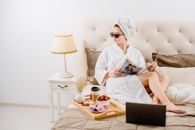 A woman in a bathrobe relaxing on the bed at home