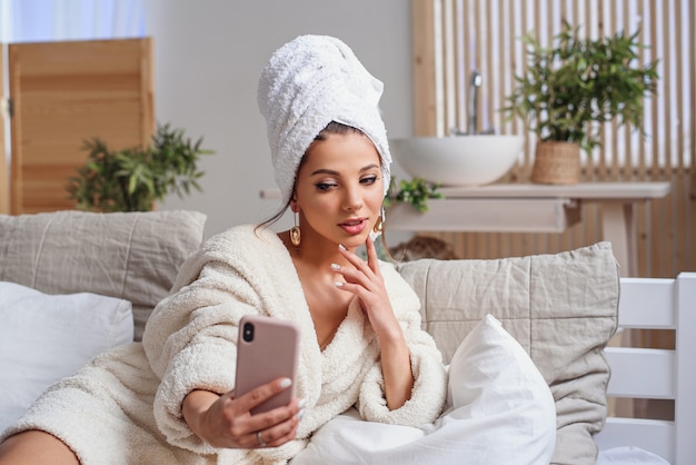 woman in bathrobe and with towel on her head making selfie