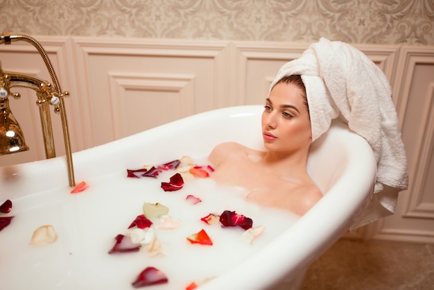 장미 꽃잎을 가진 목욕탕에있는 여자