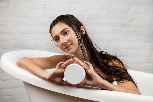 A woman in a bathtub with a white bathtub and a white tank.