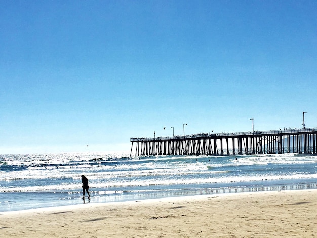 Woman on beach against clear blue sky