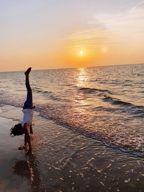 Woman on beach against sky during sunset