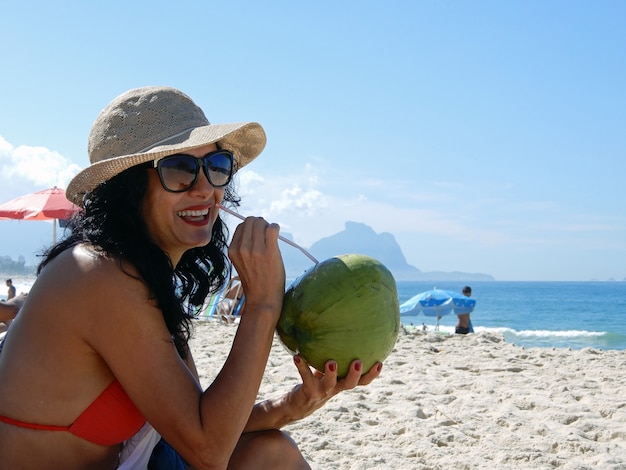 Woman on the beach drinking coconut water in Rio de Janeiro