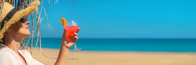 彼女の手でカクテルを持っているビーチの女性。セレクティブフォーカス。飲む。
