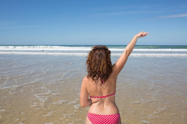 Женщина на пляже показывает пальцем