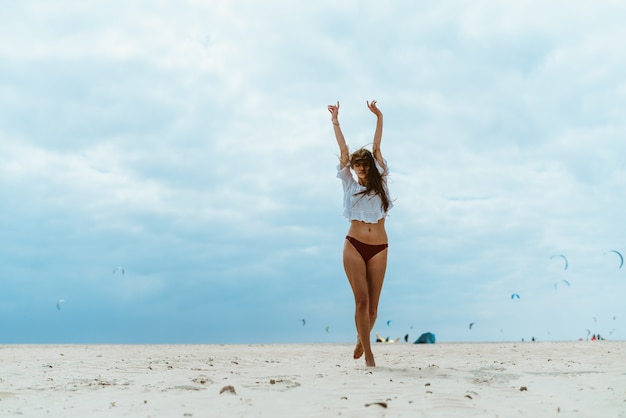 La donna sulla spiaggia si allunga in piedi con le spalle al mare
