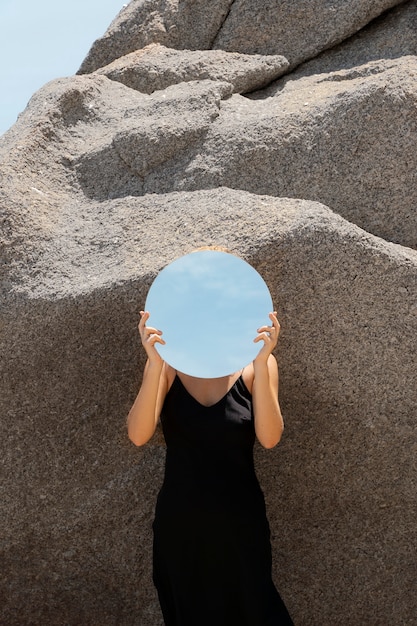 Foto donna in spiaggia in estate in posa con specchio rotondo